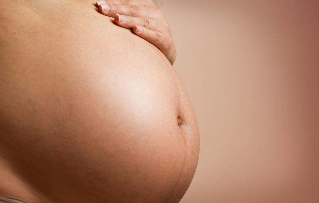 A pregnant belly being gently stroked. Image by Daniel Reche of Poços de Caldas, Brazil